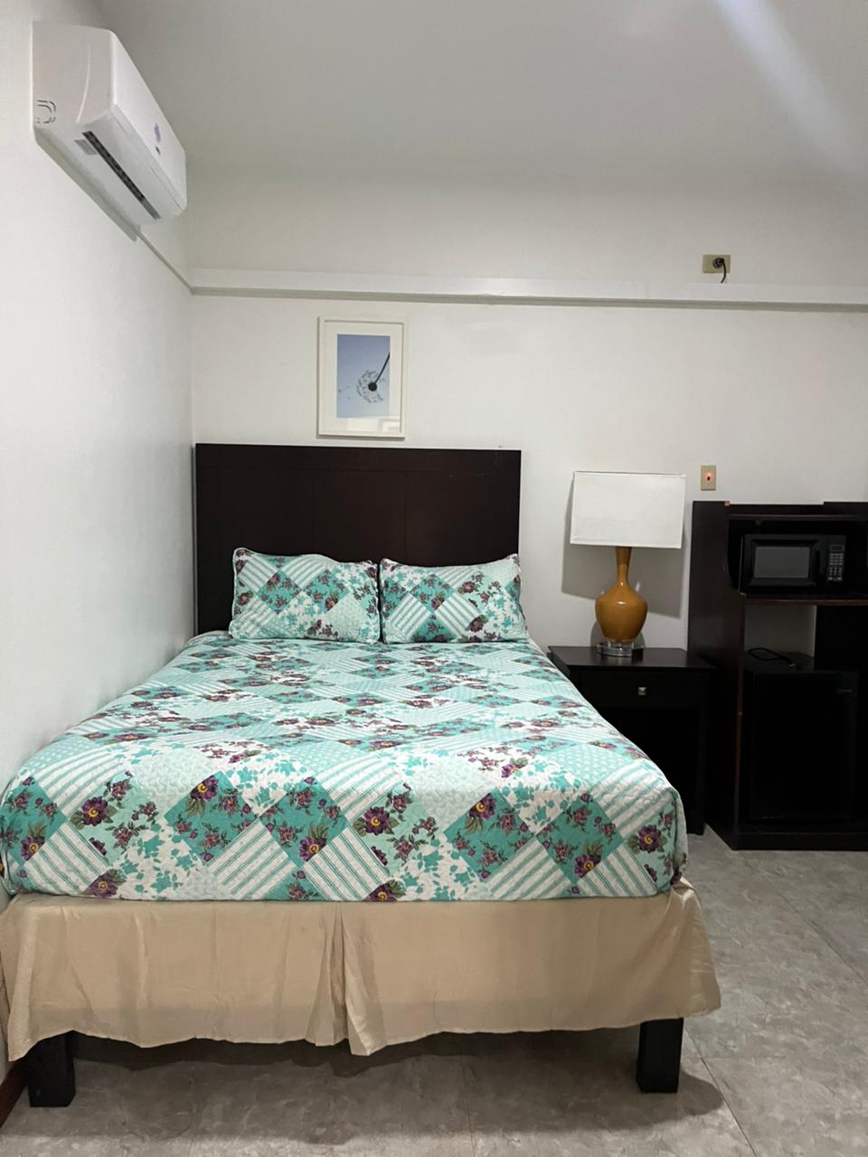 Bedroom with queen bed, air conditioning and microwave unit