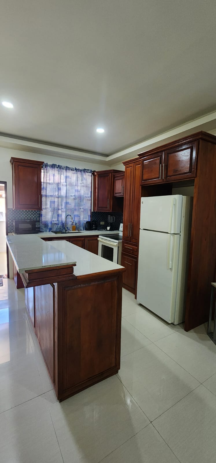 Fully equipped kitchen with a large refrigerator and stove in a three-bedroom apartment at Olympic Villas